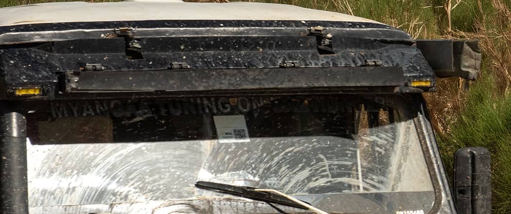 Close view of a dusty 4WD expedition vehicle's roof rack and windshield